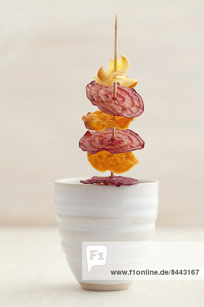 Skewered roasted vegetable chips made of parsnips  sweet potatoes  beetroots  carrots and turnips