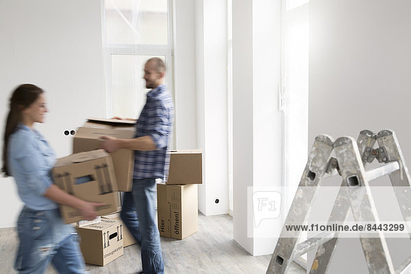 Young couple moving into new home  carrying cardboard boxes