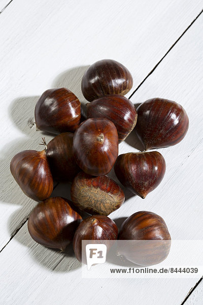 Spanish chestnuts (Castanea sativa) on white wooden table