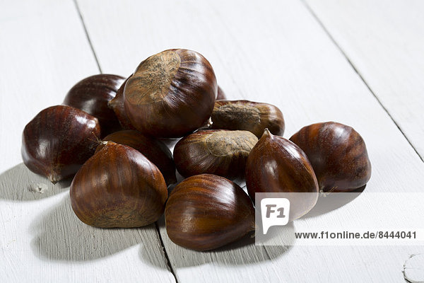 Spanish chestnuts (Castanea sativa) on white wooden table