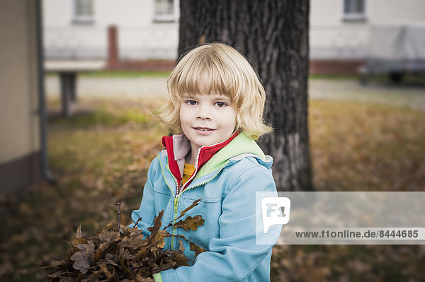 Portrait of little boy holding autumn leaves