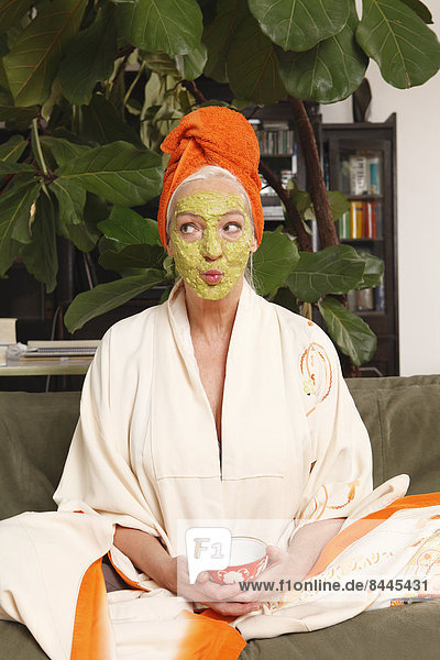 Senior woman with face mask sitting on sofa