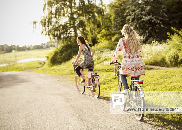 Female friends riding bicycles on country road