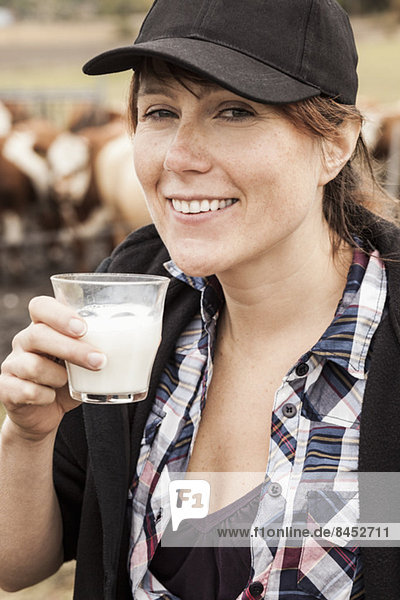 Porträt einer lächelnden Bäuerin beim Milchtrinken auf dem Bauernhof