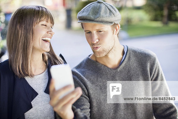 Ein glückliches Paar fotografiert sich selbst mit dem Handy im Freien.