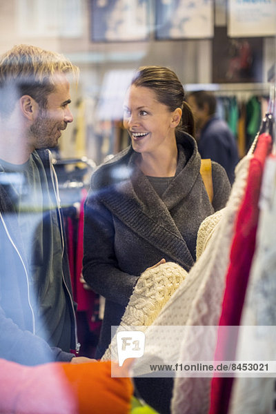 Glückliche Freunde beim Einkaufen von Pullovern im Bekleidungsgeschäft