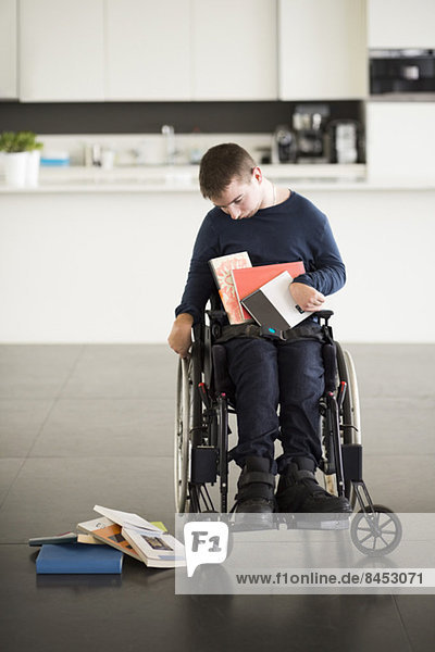 Mann mit zerebraler Lähmung beim Sitzen auf dem Rollstuhl zu Hause.