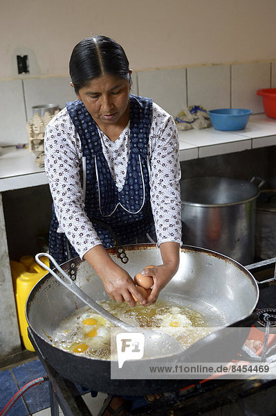 School kitchen  cook preparing fried eggs  Carmen Pampa  Yungas  Department of La Paz  Bolivia