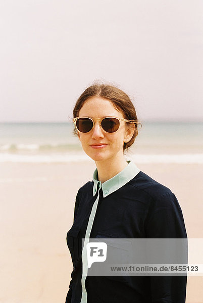 A woman wearing sunglasses on a beach.