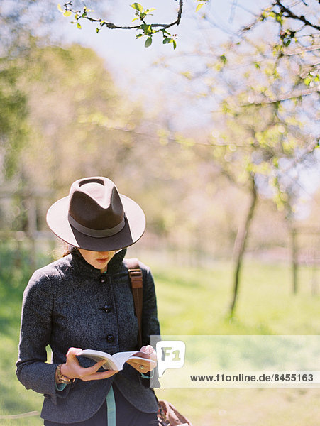 Eine Frau mit Hut  die ein Buch liest.