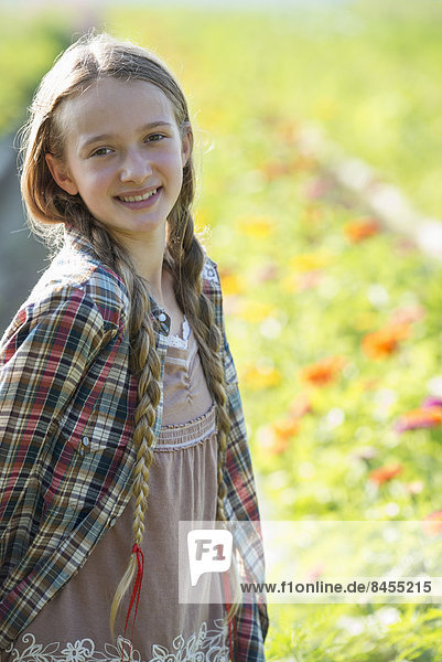 Sommer auf einem Biobauernhof. Ein junges Mädchen in einem Blumenfeld.