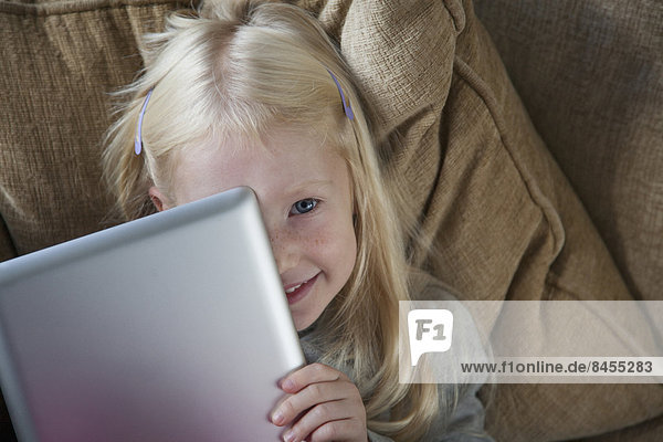 Ein junges Mädchen mit einem silbernen Laptop vor dem Gesicht.