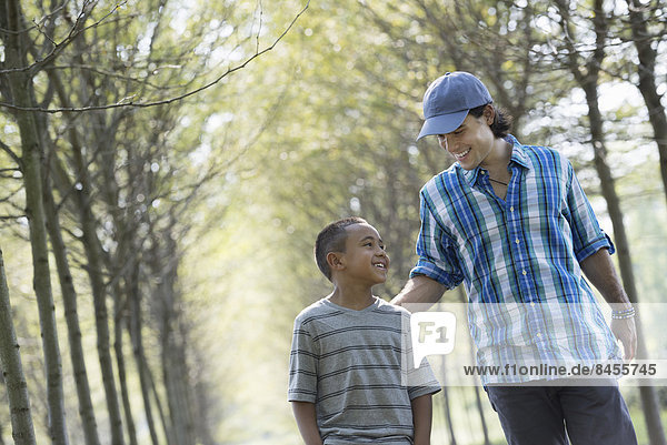 Ein Mann und ein Junge gehen eine Baumallee entlang.