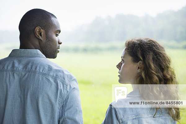 A young man and woman  a couple standing side by side. Looking at each other.