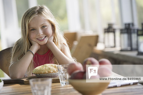 Ein junges Mädchen schaut lächelnd auf einen Kuchen.