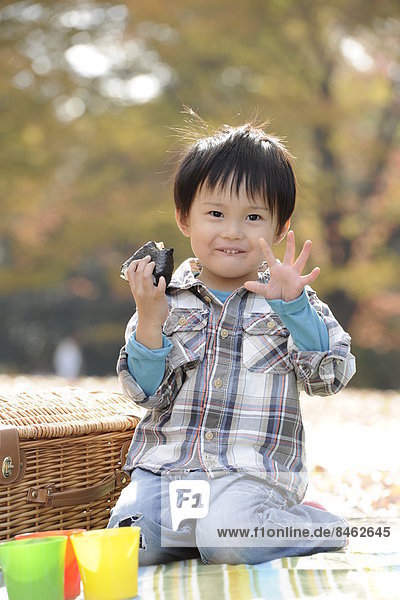 Japanese kid eating onigiri in a park