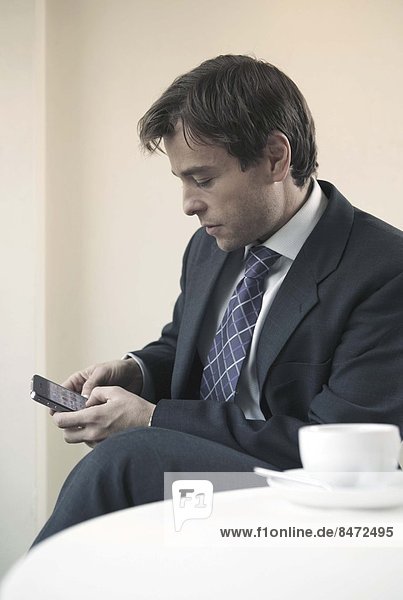 sitzend benutzen Geschäftsmann Tisch Smartphone