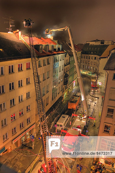 Downtown fire  roof of a residential and commercial building on fire  fire brigade in action  Munich  Bavaria  Germany