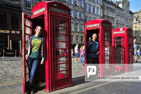 Tourists posing in three typical telephone booth in the High Street  Edinburgh  Scotland  United Kingdom