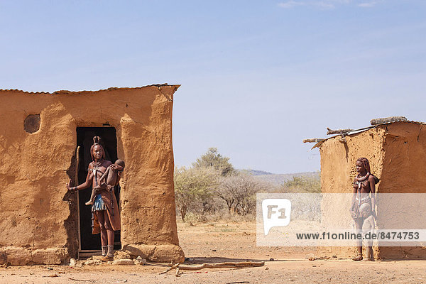 Himbafrauen mit Kindern stehen vor ihren Lehmhütten  Kaokoland  Namibia