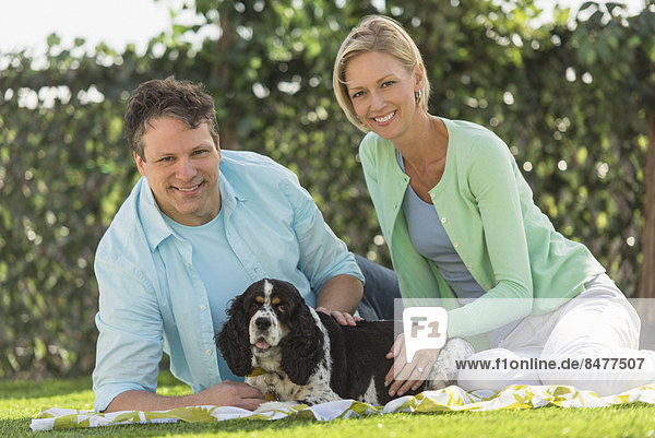 Couple with dog relaxing on grass