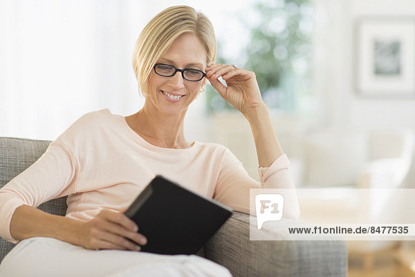 Woman sitting on sofa using tablet pc