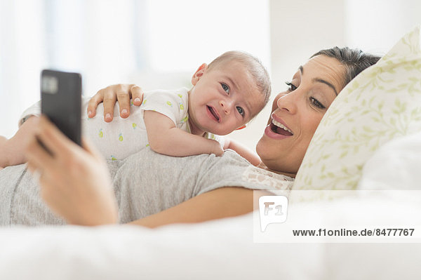 Mother photographing herself and baby boy (2-5 months) with cell phone