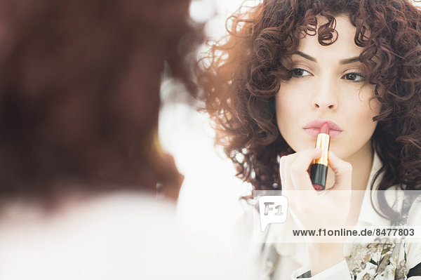 Beautiful brunette woman applying lipstick