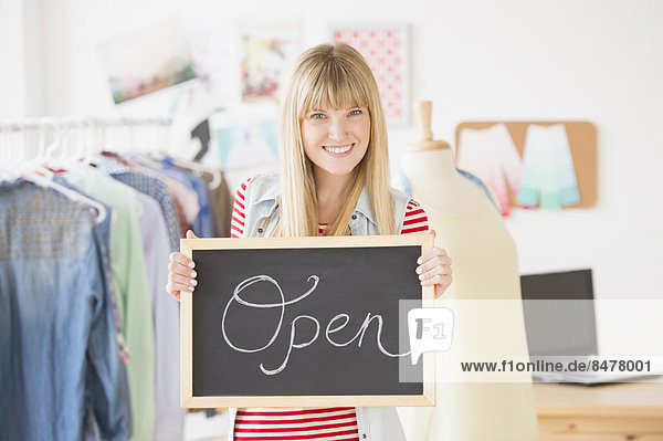 Portrait of female business owner holding open sign