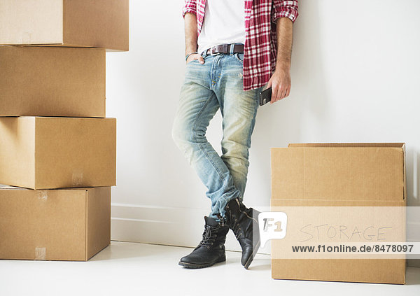 Low section of man next to stack of cardboard boxes
