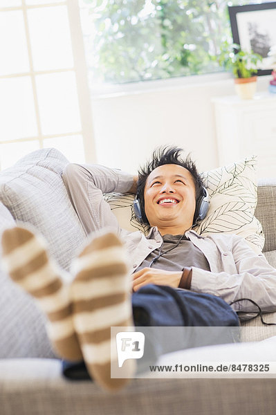 Teenage boy (16-17) lying on sofa and listening to music