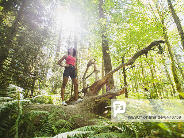 Young woman standing on log in forest