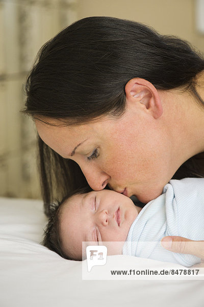Portrait of mother kissing newborn baby (0-11 months)