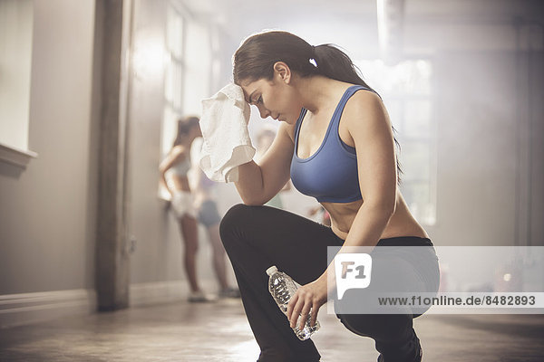 Woman wiping sweat with towel in gym