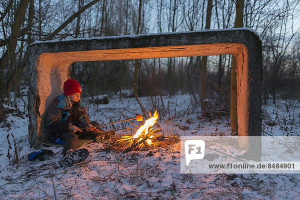 Junge sitzt am Lagerfeuer im Schnee und rˆstet Brot  Ettersberg  Weimar  Th¸ringen  Deutschland