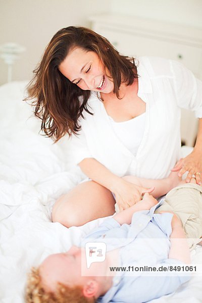 Mother playing with son on bed