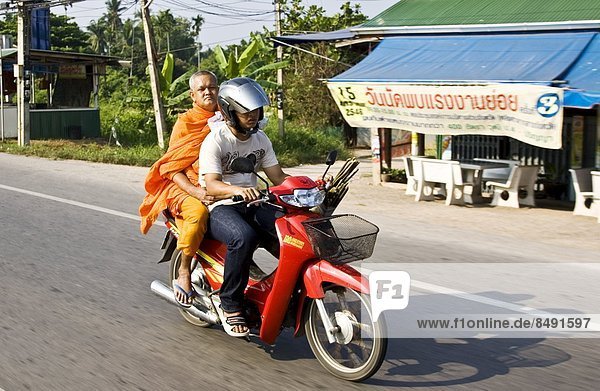 Man and a Buddhist monk travel on a motorcycle  Bangkok  Thailand