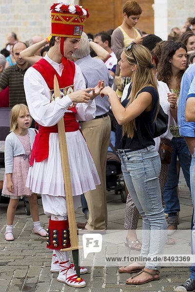 Dancer in costume chats with woman in casuals at San Fermin Fiesta at Pamplona  Navarre  Northern Spain