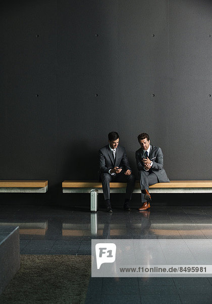 Zwei Businessmänner sitzen auf Bank  dunkler Hintergrund
