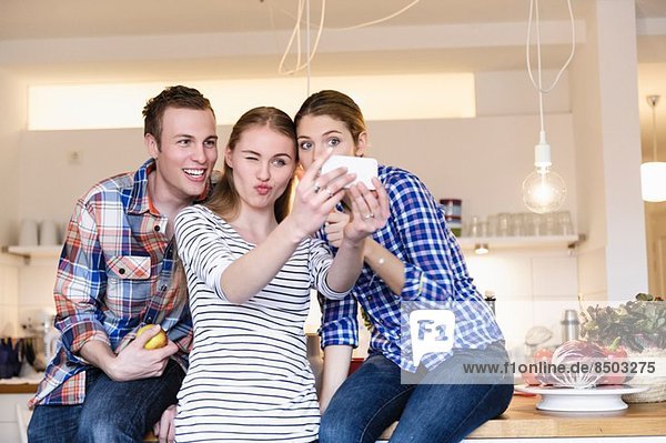 Drei junge Leute haben Spaß beim Fotografieren in der Küche