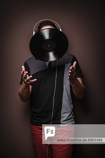 Young man wearing headphones throwing vinyl record