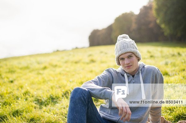 Portrait of young man sitting on grass wearing knit hat