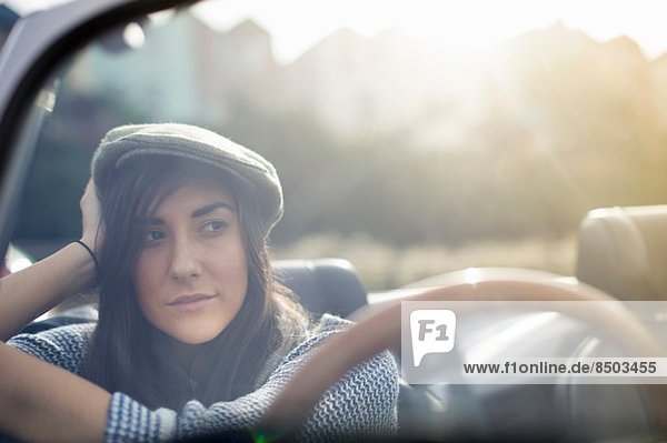 Young woman wearing flat cap in convertible