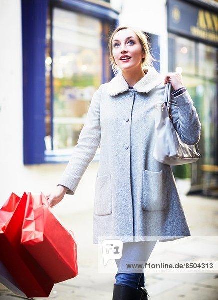 Junge Frau geht mit Einkaufstasche die Straße entlang
