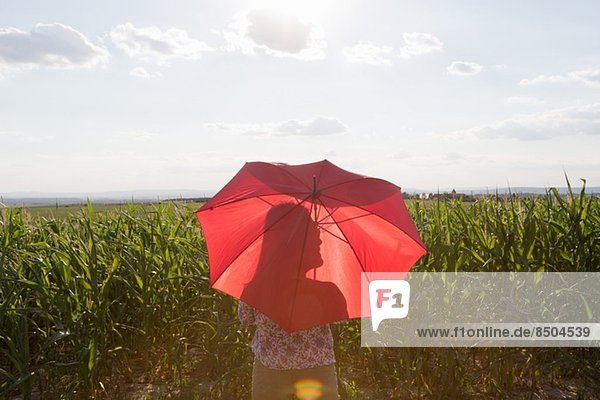 Woman standing holding red umbrella