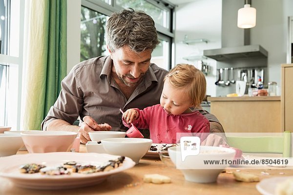Father and daughter baking in kitchen