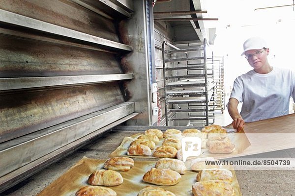 Baker putting bread onto baking sheet