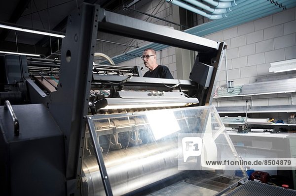 Arbeiter beim Bedienen der Druckmaschine in der Druckerei