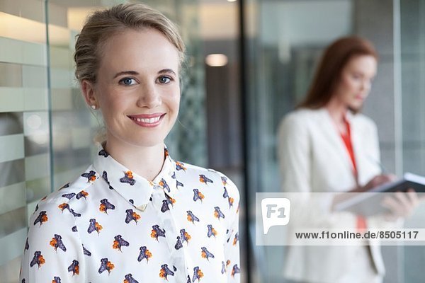 Portrait of businesswoman with colleague in background