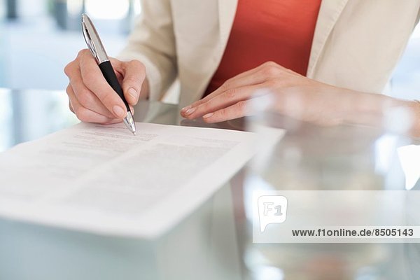 Abgeschnittenes Bild der Geschäftsfrau beim Unterschreiben von Papierkram